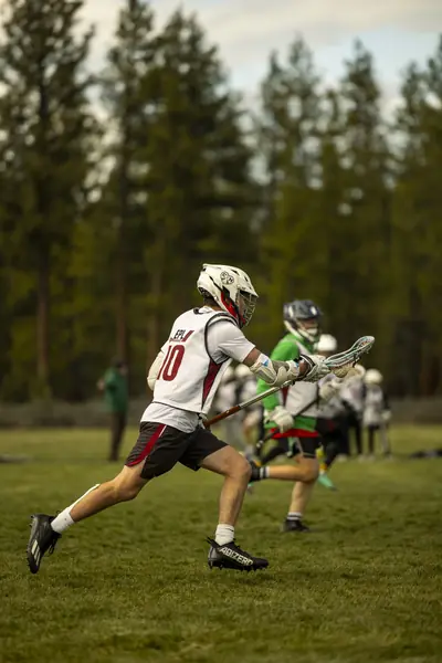 A boys player sprints upfield in front of the pines